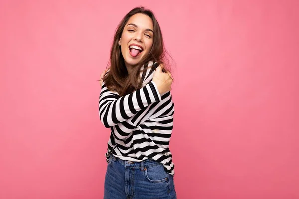 Foto de lindo atractivo bastante joven divertida divertida morena mujer usando casual rayas manga larga aislado sobre fondo colorido con espacio de copia y mostrando la lengua —  Fotos de Stock