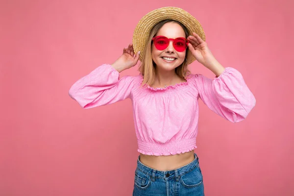 Foto de bela jovem loira positiva vestindo roupas casuais de verão e óculos de sol elegantes isolados sobre fundo colorido olhando para a câmera — Fotografia de Stock