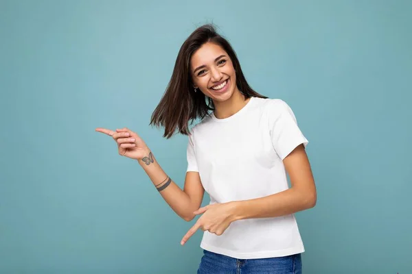 Retrato de bela fascinante emocional positivo alegre alegre promotor feminino apontando para o lado no espaço de cópia para publicidade vestindo roupa hipster isolado sobre a parede de fundo com vazio — Fotografia de Stock