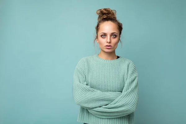 Photo of young attractive european fashion blonde woman wearing blue sweater isolated over blue background with copy space with serious expression on face. Simple and natural female person — Stock Photo, Image