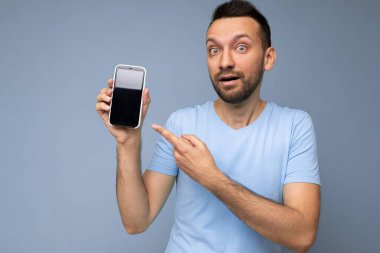 Yakışıklı, gülümseyen yetişkin bir adamın fotoğrafı. Güzel giyinen günlük kıyafetler giymiş. Arka planda izole bir şekilde duruyor.