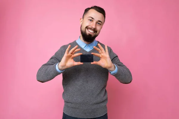 Bonito sorrindo positivo pessoa masculina vestindo roupas cotidianas isoladas na parede de fundo segurando cartão de crédito olhando para a câmera — Fotografia de Stock