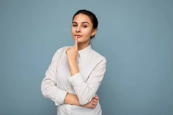 Portrét mladé atraktivní krásné přemýšlivé brunetky žena s upřímnými emocemi na sobě ležérní sriped bílé košile izolované přes modré pozadí s kopírovacím prostorem a myšlení. Myšlenkový koncept — Stock fotografie