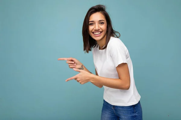 Retrato de bela fascinante emocional positivo alegre alegre promotor feminino apontando para o lado no espaço de cópia para publicidade vestindo roupa hipster isolado sobre a parede de fundo com vazio — Fotografia de Stock