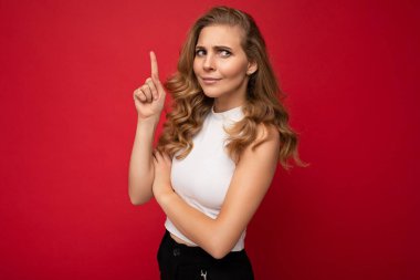 Hoş, hoş, düşünceli, sıradan kıyafetler giyen yetişkin bir kadının fotoğrafı. Arka planda izole edilmiş, fotokopi alanı ellerle boş alanı gösteren ve soru soran bir kadın.