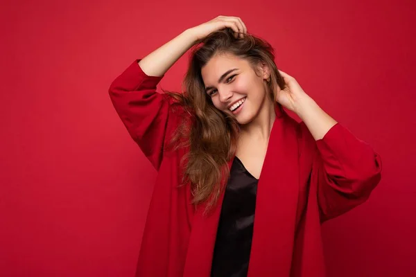 Foto portrét krásné šťastně se usmívající mladé brunet žena ve stylovém červeném svetru. Sexy bezstarostná žena pózující izolovaně na červeném pozadí. Pozitivní model ukazuje upřímné emoce — Stock fotografie