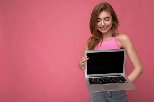 Frumos zâmbind fericit tânără femeie care deține laptop-ul computerului uitându-se în jos la netbook având distracție purtând haine inteligente casual izolate pe fundal de perete — Fotografie, imagine de stoc