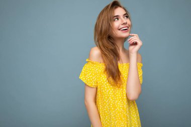 Çekici, mutlu, duygusal bir kadının arka plandaki duvarda izole edilmiş, rahat kıyafetler giyerek zehirlenmesinin fotoğrafı.