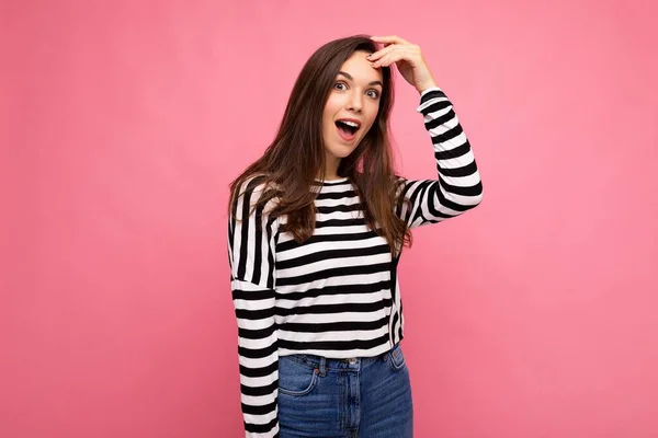 Photo of young amazed shocked positive beautiful brunette woman with sincere emotions wearing casual striped pullover isolated on pink background with copy space — Stock Photo, Image