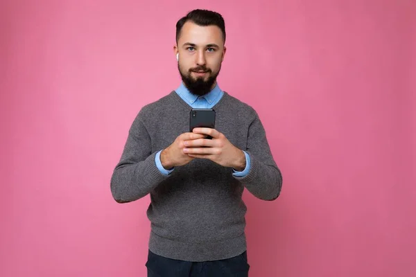 Foto tiro de calma concentrada sério bonito bonito jovem vestindo roupas elegantes casuais poising isolado no fundo com espaço vazio segurando na mão e usando mensagens de telefone celular — Fotografia de Stock