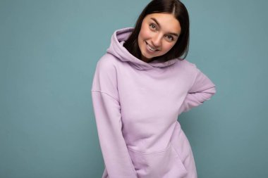 Güzel, pozitif gülümseyen, şık kıyafetler giyen, renkli bir arka planda dikilip fotokopi çeken ve kameraya bakan yetişkin bir kadının fotoğrafı.