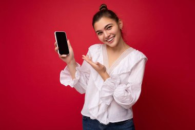 Güzel, gülümseyen genç bir kadının resmi. Günlük kıyafetlerini giymiş. Arka planda izole bir şekilde duruyor.