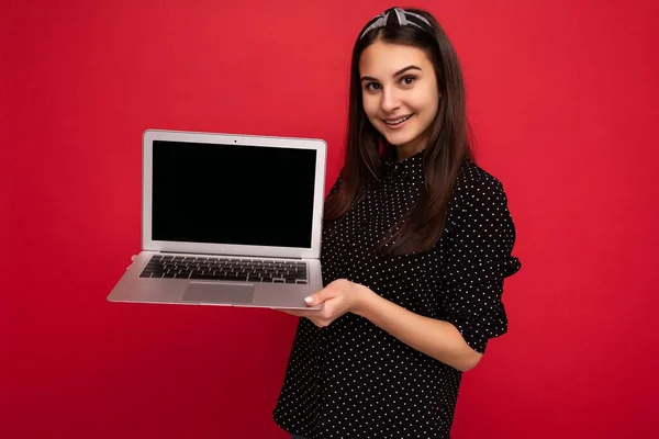 Fotografie de fată frumoasă zâmbitoare purtând haine negre ținând laptop-ul computerului uitându-se la camera izolată pe fundal de perete colorat — Fotografie, imagine de stoc