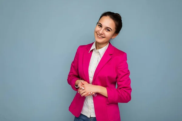 Φωτογραφία πορτρέτο του νεαρού ωραίο γοητευτικό όμορφη θετική χαμογελαστή μελαχρινή γυναίκα με ειλικρινή συναισθήματα φορώντας casual λευκό πουκάμισο και κομψό ροζ σακάκι απομονώνονται σε μπλε φόντο με αντίγραφο χώρο — Φωτογραφία Αρχείου