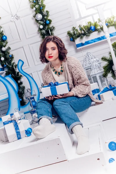 Pretty young girl in jeans and a cardigan with Christmas gifts c — Stock Photo, Image