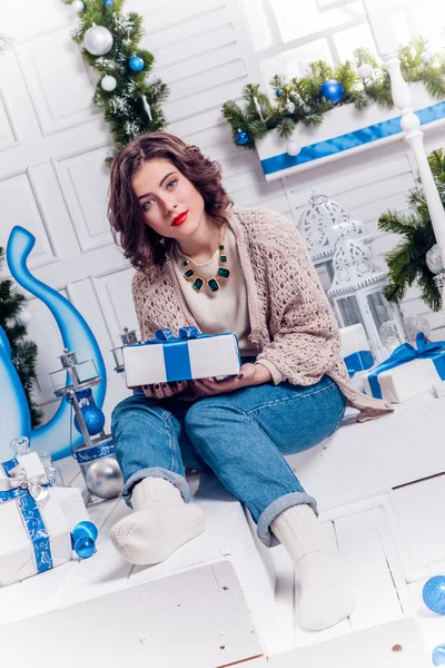 Hübsches junges Mädchen in Jeans und Strickjacke mit Weihnachtsgeschenken — Stockfoto