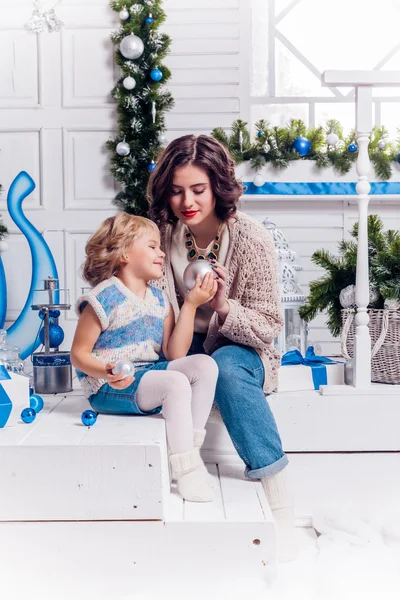Chica sentada con su hermana cerca de un árbol de Navidad y sonriendo —  Fotos de Stock