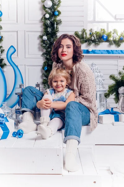 Dívka sedí s její sestrou u vánočního stromu a s úsměvem — Stock fotografie