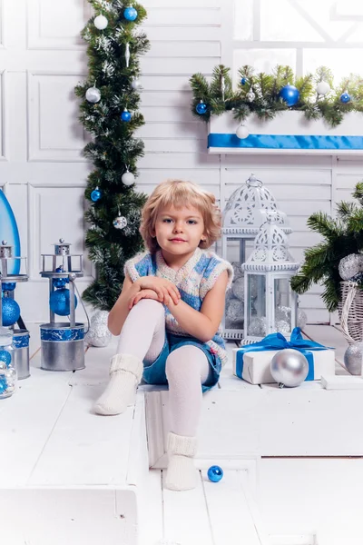Bir Noel ağacı yanında oturan küçük gülümseyen güzel kız ve — Stok fotoğraf