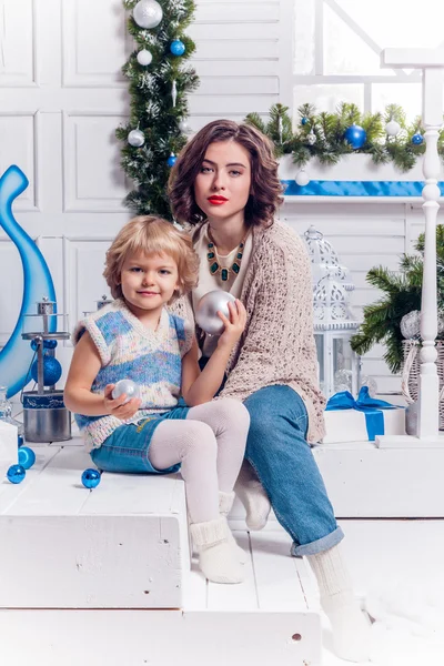 Chica sentada con su hermana cerca de un árbol de Navidad y sonriendo —  Fotos de Stock