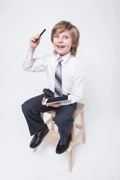 Niño en un traje de negocios y corbata sosteniendo una tableta — Foto de Stock