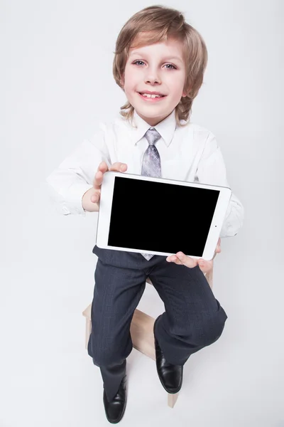 Niño en un traje de negocios y corbata sosteniendo una tableta — Foto de Stock