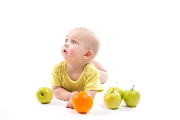 Cute smiling baby lying on his stomach among fruits and looking — Stock Photo, Image