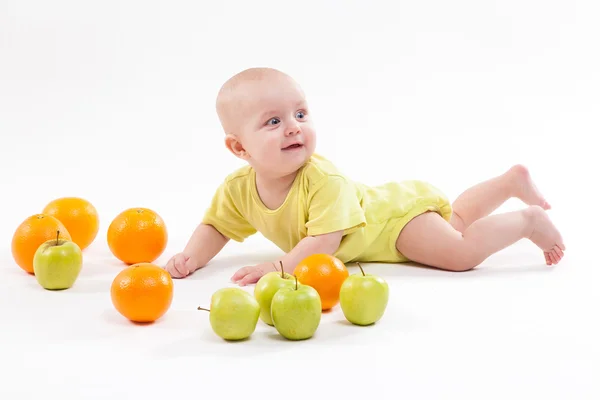 Cute surprised baby looks at green apple on a white background — Stock Photo, Image
