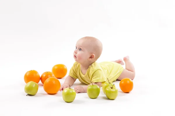 Cute smiling healthy child lies on a white background among frui — Stock Photo, Image