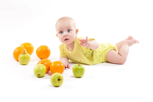Cute smiling healthy child lies on a white background among frui — Stock Photo, Image
