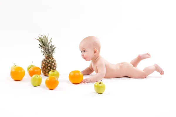 Cute smiling healthy child lies on a white background among fruit — Stock Photo, Image