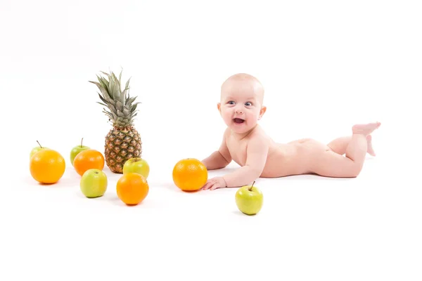 Uśmiechający się ładny zdrowe dziecko leży na białym tle wśród owoców — Zdjęcie stockowe