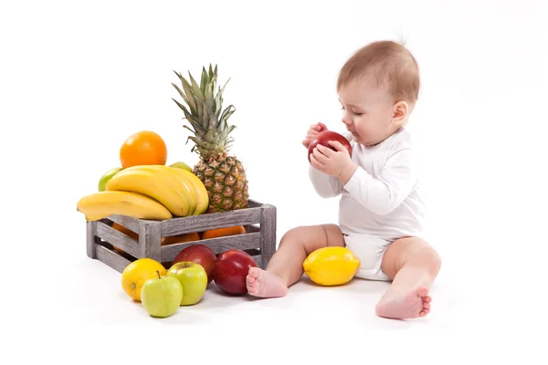 Глядя на фрукты симпатичный улыбающийся ребенок на белом фоне среди фру — стоковое фото