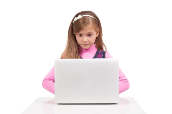 Schoolgirl on a white background in surprise looks in the laptop — Zdjęcie stockowe