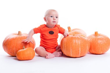 Beautiful baby in orange t-shirt on a white background sits next