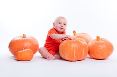 Beautiful baby in orange t-shirt on a white background sits next