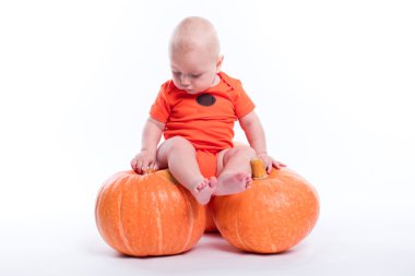 Beautiful baby in orange t-shirt on a white background sitting o