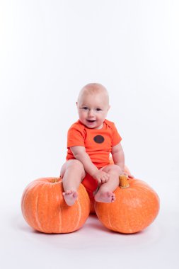 Beautiful baby in orange t-shirt on a white background sitting o