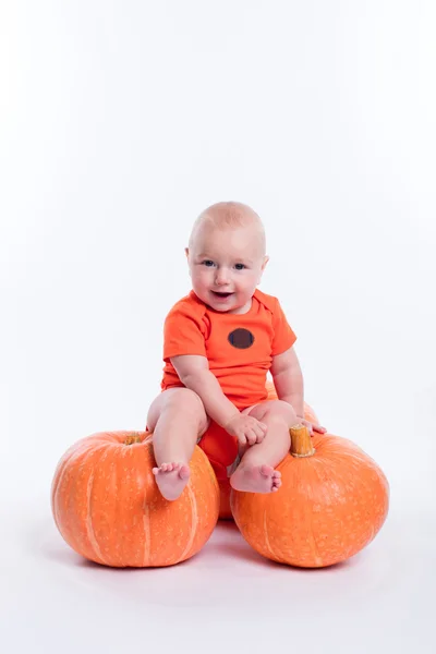 Beautiful baby in orange t-shirt on a white background sitting o — Zdjęcie stockowe
