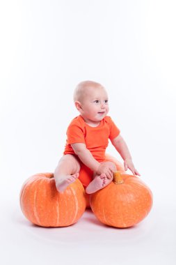 Beautiful baby in orange t-shirt on a white background sitting o