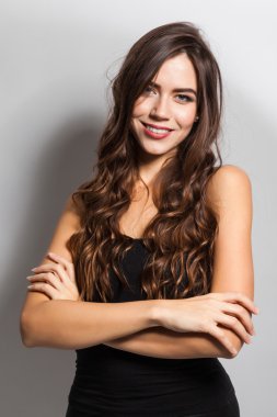 Brunette with magnificent hair with a snow-white smile in a blac