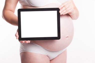 Pregnant woman holding a tablet horizontally at the level of the