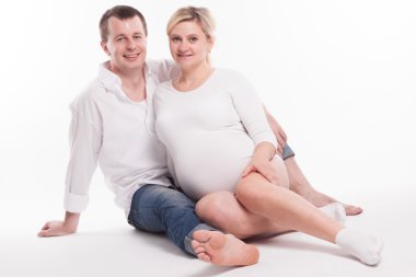 young dad in jeans and a white shirt and a pregnant woman in a w