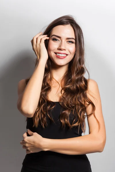 Brunette with magnificent hair with a snow-white smile in a blac — Stockfoto