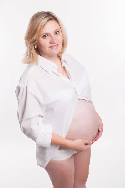 Donna bionda incinta in camicia bianca in piedi su un backgro bianco — Foto Stock