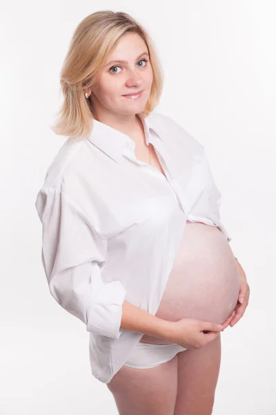 Mujer rubia embarazada con camisa blanca de pie sobre un fondo blanco —  Fotos de Stock