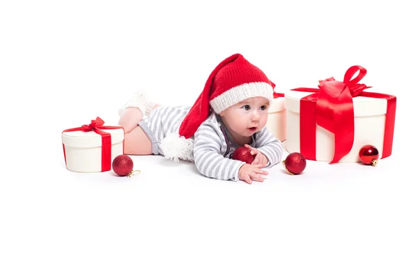 Симпатичный ребенок в красной новогодней кепке с улыбкой на лице, лежащий — стоковое фото