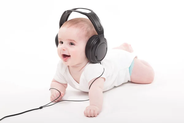 Encantador bebé sobre un fondo blanco con auriculares escuchando — Foto de Stock