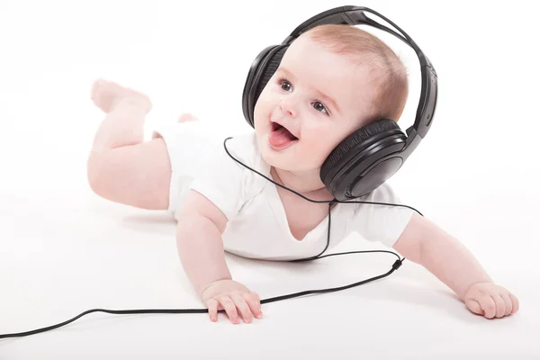 Encantador bebé sobre un fondo blanco con auriculares escuchando — Foto de Stock