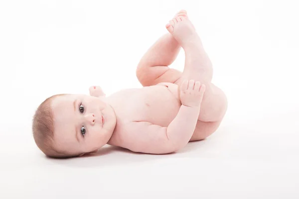 Bebé desnudo se acuesta sobre su espalda y mira a la cámara —  Fotos de Stock